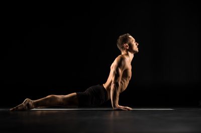 Man performing Bhujangasana ot Cobra Pose on yoga mat
